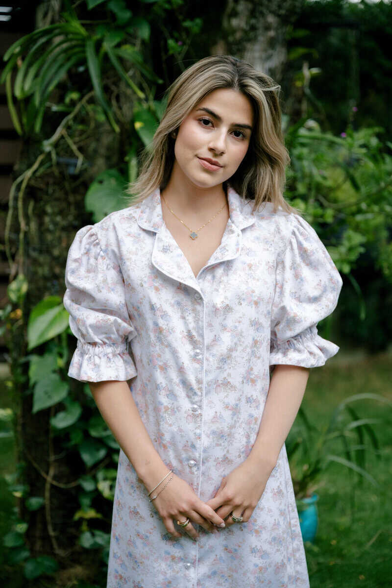 Woman wearing a floral nightshirt in a lush garden setting.